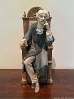 Front view of the Lladro porcelain judge figurine showing detailed facial features, judge's attire, and chair design.