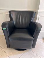 Front view of the black faux leather swivel lounge chair, showing padded seat, back, and armrests.