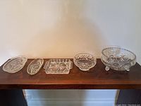 Five vintage crystal and glass items displayed on wood surface, including two bowls and three serving dishes.