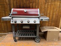 Front view of grill closed showing side tables, wheels and nearby box