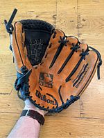 Wilson baseball catchers glove with brown leather palm, black leather back, and black lacing. The glove has a basket web and shows signs of wear and fraying.