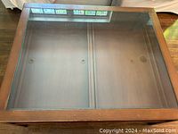Top view of solid wood coffee table showing clear glass top and two display drawers.