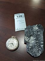 Westclox Pocket Ben pocket watch and fossil stone side by side with auction tag