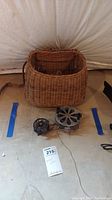 Photo showing full view of the wicker creel basket with the two metal fly reels in front on the floor.