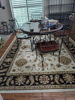 Full view of the area rug under dining table showing the central beige floral medallion pattern and black border with floral details.
