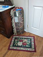 Rolled Karastan runner rug with traditional pattern next to floral door mat.