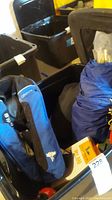 Photo showing blue West Marine Offshore inflatable PFD, dry bag, and other gear in black plastic bin.