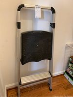 Folded lightweight aluminum step stool with black plastic steps and platform. Rubber feet to prevent floor scratching.