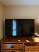 Full front view of 42-inch Fire TV on wooden dresser with remote in front.
