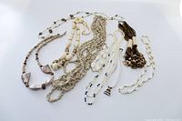 Photo showing all 10 assorted white and cream tone costume jewellery necklaces laid out together against white background.