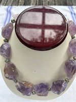Front view of chunky amethyst and freshwater pearl necklace displayed on a bust. Shows large irregular purple amethyst stones and small pearl spacer beads with hook closure.