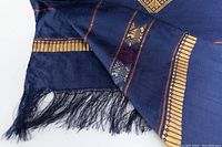 Close-up of the corner showing the silk fabric, gold embroidery, and fringe detail