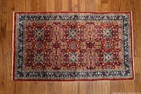 Full view of Chinese silk carpet showing detailed floral and geometric pattern in red, blue, and beige tones