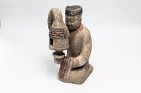 Front view of the handmade Tang style figurative clay lantern showing the figure holding the lantern, facial details, and paint remnants.