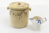 Photo showing yellow biscuit jar with floral hand painted decoration and a lid, alongside an English creamer with blue flowers.