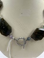 Close-up of toggle clasp and beads near closure showing twisted rope style toggle and small round beads adjacent to large labradorite bead.