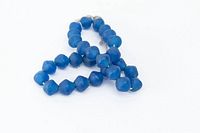 Blue extra large recycled glass beads roughly 1 inch each on gray string, arranged loosely with some beads forming a loop.