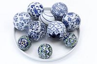 Top view of 10 porcelain decorative spheres on a white round tray, showing blue and white Chinese porcelain balls and smaller blue, white, green glazed Uzbek spheres