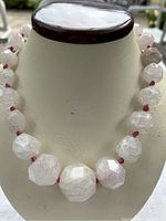 Necklace displayed on white bust, showing graduated faceted pink quartz beads with dark pink cord knotted between each bead.