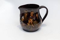 Front side view showing the detailed Dickens character illustrations on the jug's dark brown glossy surface.