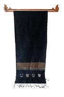 Full length view of black silk textile hanging on wooden hanger, displaying woven pattern near one end and fringe details.