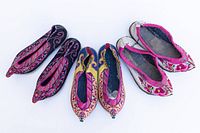 Three pairs of vintage handmade ladies shoes with intricate embroidery, photographed from above to show colors and patterns.