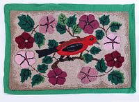 Full view of vintage hooked rug with central red cardinal surrounded by flowers and green leaves, bordered with green felt.