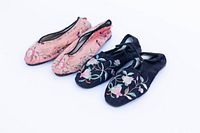 Two pairs of vintage Chinese embroidered silk ladies shoes, one pink and one black, displayed side by side on a plain white background.