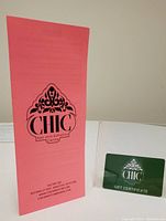 Green $100 gift certificate card displayed in a clear stand, accompanied by a pink informational brochure featuring the Chic Hair and Esthetics Centre logo and contact information.