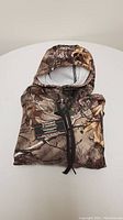 Folded polyester camouflage hoodie with deer motif and Village Custom label.
