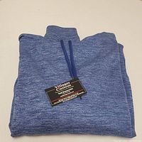 Folded blue heather polyester men's medium hoodie with tag from Village Custom visible.
