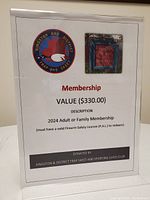 Photo of printed membership display for 2024 Adult or Family Membership from Kingston & District Trap and Skeet Club, showing value and redemption requirements.