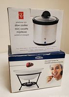 Photo showing the boxed President's Choice slow cooker with 500ml capacity and the boxed Trudeau 7-piece chocolate fondue set.