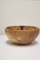 Photo of a spalted maple woodturned bowl showing natural wood tones, spalting lines, a smooth finish, and some natural cracks inside the bowl.