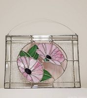 Stained glass panel showing the front view of the panel with pink flowers and green leaves in an oval shape, surrounded by clear textured glass and metal frame.