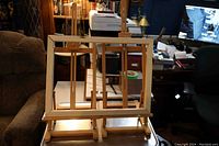 View showing two wooden artist easels set up side by side on a table in a room with bookshelves and computer desk.