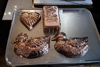 Four copper molds on metal tray showing all included items and details