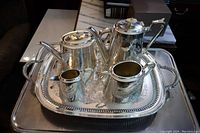 Overview of the complete silver plated Victorian tea set on its footed tray with hammered texture and polished finish.