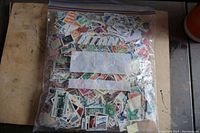 Photo of sealed plastic bag filled with a large quantity of mixed used stamps.