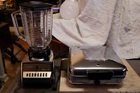 Osterizer Classic VIII blender and Magic Maid chrome waffle iron side by side showing overall condition