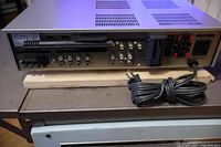 Rear view showing multiple RCA audio input/output connections, speaker terminals, antenna connectors, power cord attached.