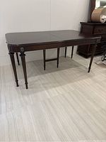 Full view of walnut dining table in closed position showing ten legs and top surface