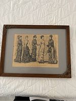 Framed lithograph depicting five women in period dresses from 1880, wooden frame with corner decoration, blue matting