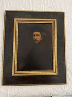 Full view of framed artwork showing man with beret inside bronze and black wooden frame.