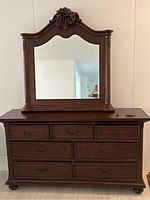 Front view showing dresser with attached mirror featuring carved decorations and bronze handles on drawers.
