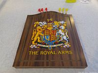 Wood-grain inside lid of the case with 'The Royal Arms' crest and 6 darts with plastic flights inserted.