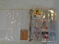 Binder open displaying individual hockey cards in clear sleeves with player photos and stats visible.