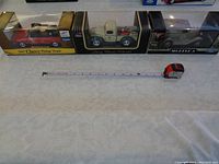 Three boxed die cast pickup trucks shown side by side with measuring tape displaying approximately 7 inch length.