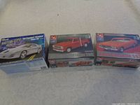The three model car kits displayed side by side, showing the 1978 Dodge Pickup and 1969 Chevelle SS boxes sealed, and the 1998 Pontiac Firebird box open.