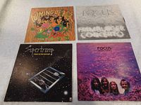 Four vinyl LP record album covers laid flat showing colorful and artistic designs for rock bands Supertramp, Focus x2, and Five Man Electrical Band.